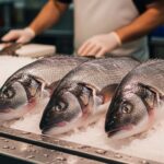 Fresh whole branzino fish on ice at fish market counter with price tag showing cost per pound, professional seafood display